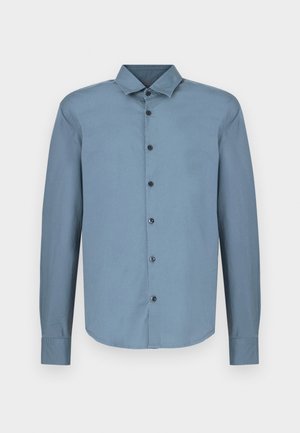 Šviesiai mėlyna ilgomis rankovėmis marškiniai iš medvilnės, turintys smailų apykaklį, užsegimą priekyje su juodais mygtukais. Lygus audinys, išlenkta apačia.