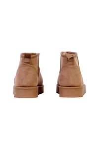 Botas de tobillo de ante color marrón claro con una textura suave, punta redondeada y suela resistente de goma. Incluyen una lengüeta en la parte trasera y detalles de costura.