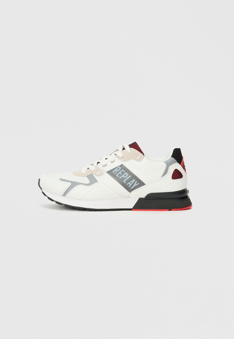 Sneakers ar galvenokārt baltu augšdaļu ar pelēkiem un sarkanajiem akcentiem, strukturētām paneļiem, plakaniem šņorēm un melnu zoli ar sarkanām detaļām.