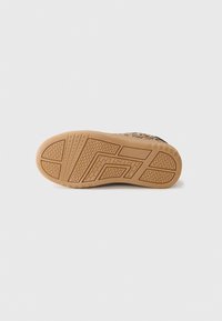 Semelle d'une chaussure de sport imprimée léopard avec un motif de semelle en caoutchouc tan texturé sur fond blanc uni.