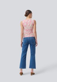 Pink tie-dye tank top with a fitted design, paired with straight-leg blue denim jeans featuring back pockets and a casual cut.