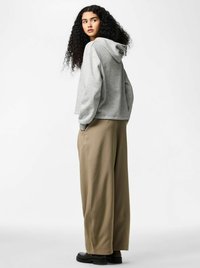 Hall hõlmatud kapuutsiga džempripluus, mida täiendavad beežid laiapõhjalised püksid. Komplekti kuuluvad taskud ja sile, pehme tekstuur. Mustad jalatsid lõpetavad välimuse.