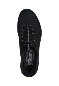 Zapatilla negra de Skechers tipo slip-on con parte superior de malla, cordones elásticos y plantilla acolchada. Cuenta con un pequeño logo en el lado y un patrón texturizado.
