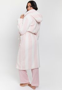 Accogliente vestaglia a righe rosa e bianca con cappuccio, dal texture morbida e soffice, con vita legata e pantaloni da notte rosa a costine coordinati. Design caldo e confortevole.