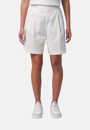 Pantaloni corti bianchi in cotone con pieghe laterali, vita alta e vestibilità rilassata. Abbinati a sneaker bianche con design in rete e pelle.