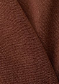 Tissu brun texturé à surface tissée ; les plis révèlent un matériau doux et durable, adapté à diverses applications.