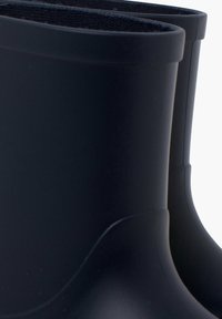 Bottes en caoutchouc noires avec une texture lisse, de hauteur courte et des bords arrondis. Dotées d'une doublure douce et moelleuse en haut pour plus de confort.