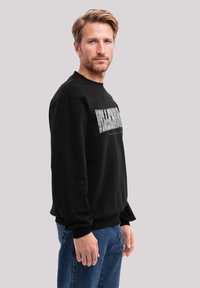 Schwarzer Sweatshirt mit grafischem Textdesign auf der Vorderseite. Hat gerippte Bündchen und Saum, hergestellt aus einem glatten, weichen Stoff.