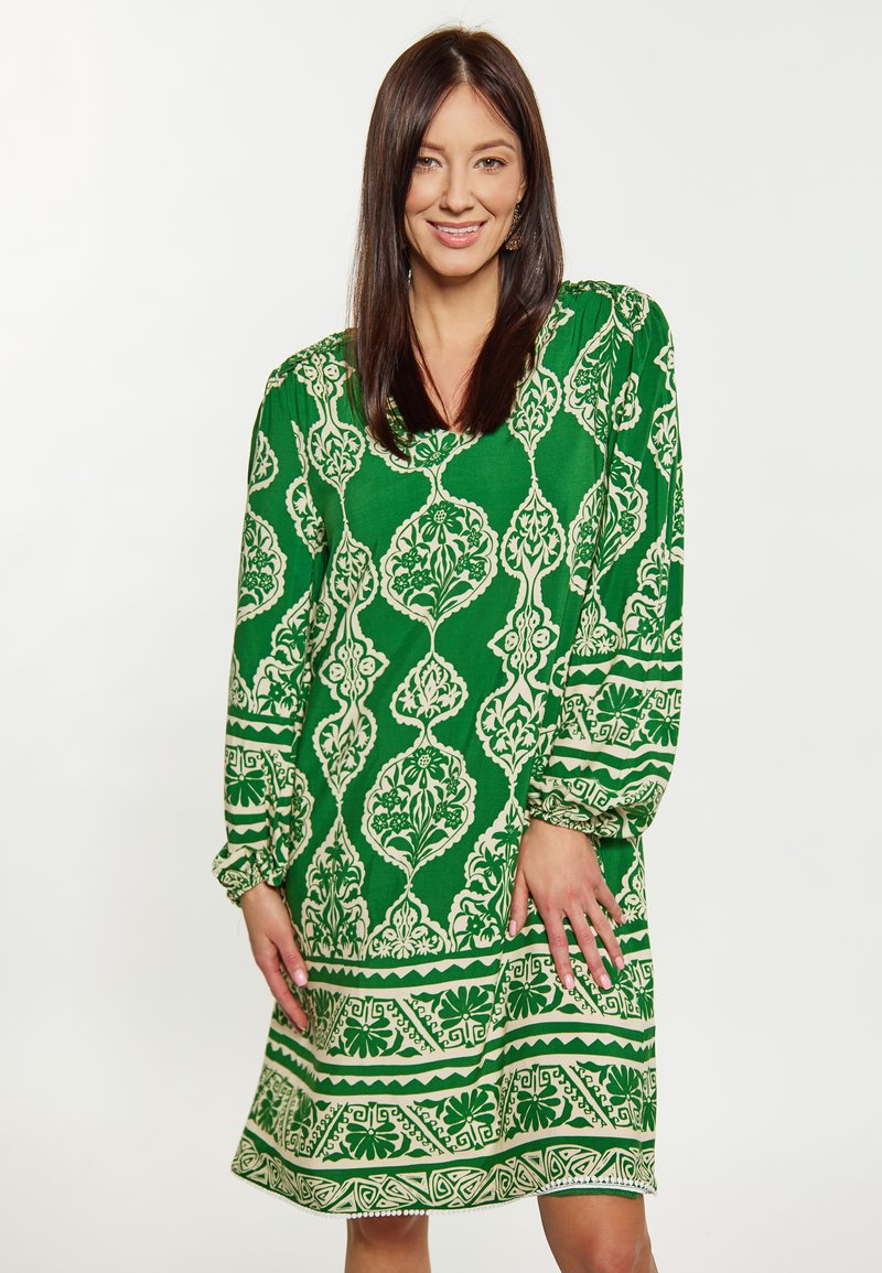 Rochie verde cu un pattern floral și geometric alb, mâneci bufante lungi, decolteu în V și tiv evazat.