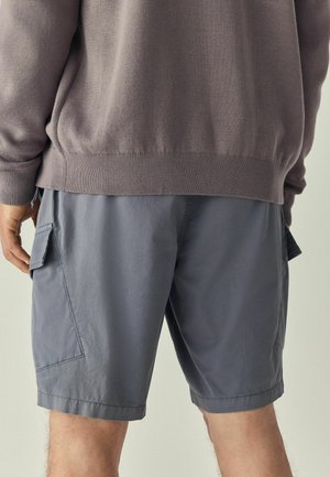 Shorts cargo gris en tissu léger, dotés de poches latérales, d'une coupe décontractée et d'un design simple et épuré.