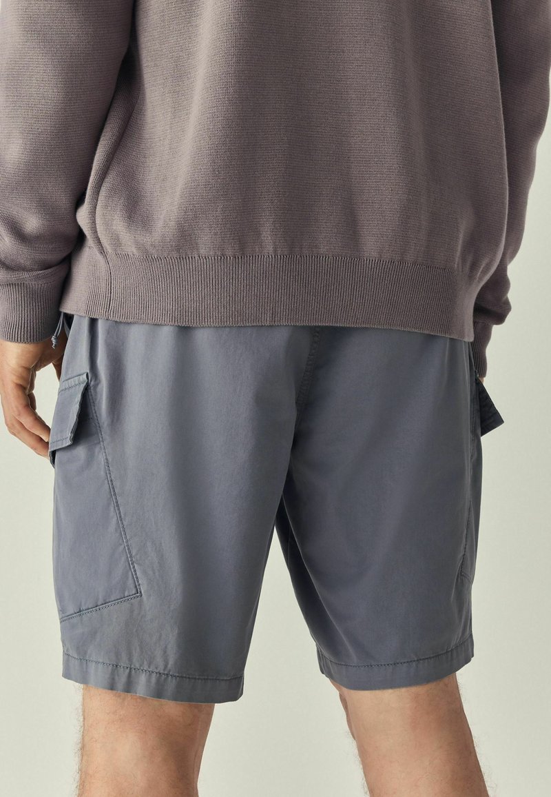 Shorts cargo gris en tissu léger, dotés de poches latérales, d'une coupe décontractée et d'un design simple et épuré.