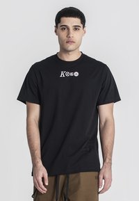 Černé bavlněné tričko s krátkým rukávem, na hrudi s malou bílou grafickou značkou. Jednoduchý design, kulatý výstřih.