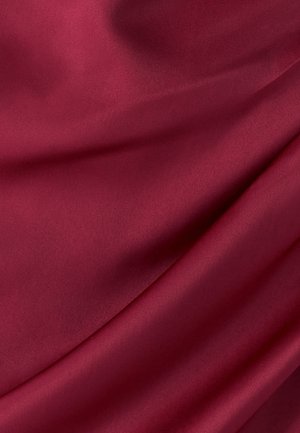 Deep red satin fabric with a smooth, glossy texture, exhibiting subtle folds and draping that highlights its softness and depth of color.