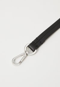 Sangle en cuir noir avec quincaillerie en métal argenté, dotée d'un mousqueton et d'une couture détaillée sur toute sa longueur.