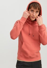 Koraalkleurige hoodie met een voorzak, trekkoord in de capuchon, ribgebreide boorden en onderrand. Zachte textuur, casual ontwerp en een standaard pasvorm.