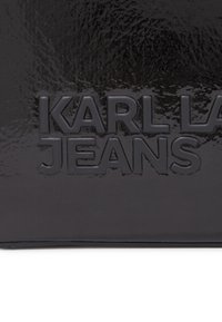 Pelle nera testurizzata con lettering in rilievo "KARL LAGERFELD JEANS." Finitura liscia e lucida con una leggera lucentezza e forma solida.