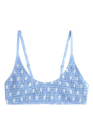 Bralette bleu clair smockée avec fines bretelles ajustables et petit motif de points blancs irréguliers.