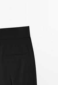 Pantalon noir taille haute avec une seule poche passepoilée au dos sur fond blanc uni.