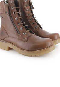 Botines marrones de cuero con punteras redondeadas, ojales metálicos y cordones, con cremallera lateral y suelas de goma. Textura suave y diseño clásico.