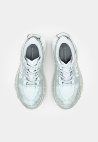 Light gray running shoes with a textured, patterned upper, lace closure, and a cushioned sole. Features a prominent logo on the side.