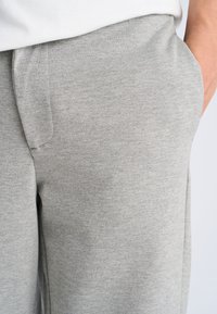 Gray sweatpants with a textured fabric, featuring a loose fit, side pockets, and a relaxed waistband.