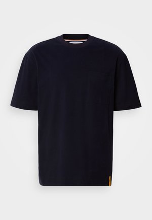 T-shirt a maniche corte di colore blu navy, realizzato in cotone. Presenta una tasca sul petto e una piccola etichetta arancione sul lato. Collo rotondo. Design semplice.