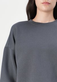 Sweatshirt cinza feito de algodão macio, com decote redondo, mangas longas e um ajuste descontraído com mínimo detalhe de costura.