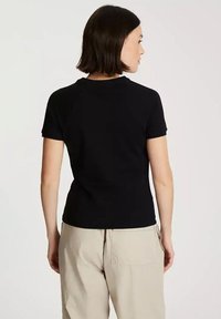 Czarna bawełniana koszulka z krótkim rękawem i okrągłym dekoltem, o gładkiej fakturze i dopasowanym kroju, widoczna z tyłu.