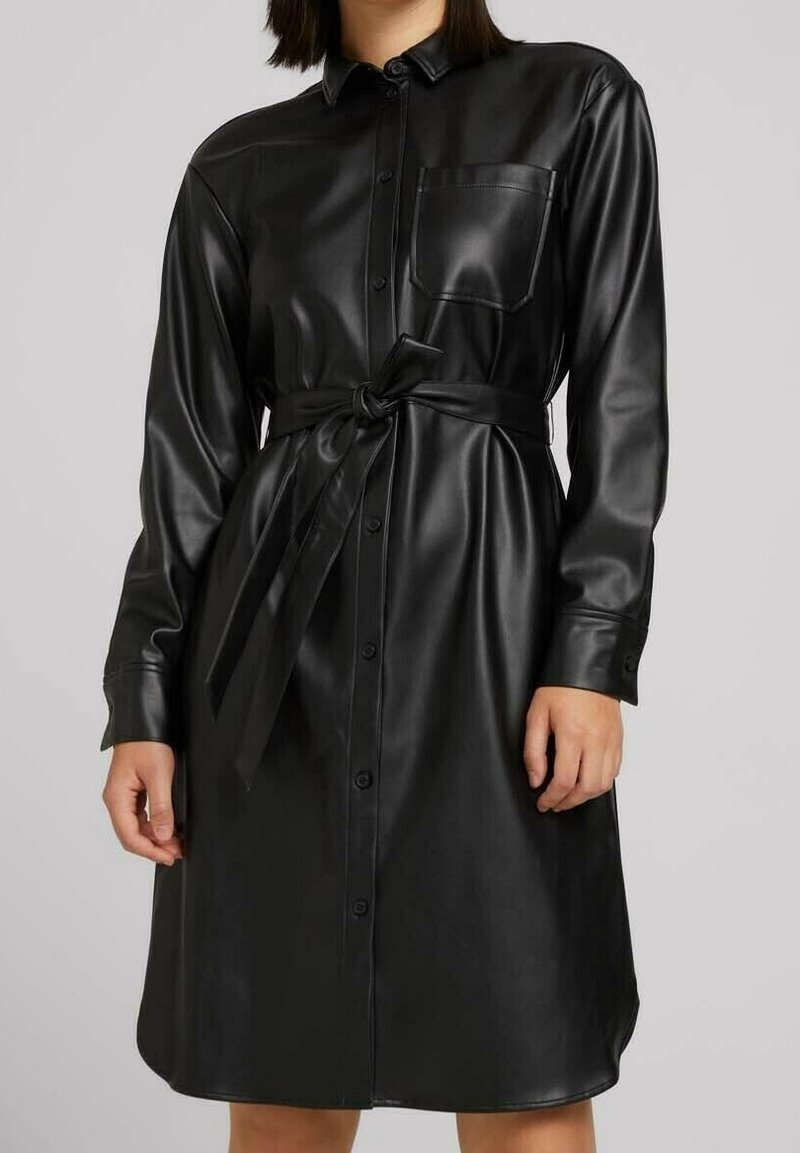 Schwarzes Kleid aus Kunstleder mit durchgehender Knopfleiste, langen Ärmeln, Brusttasche und gebundenem Gürtel in der Taille. Glatte Textur.