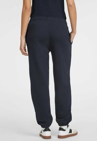 Navy blue sweatpants featuring a drawstring waist, side pockets, and ribbed cuffs. Made of soft, textured fabric with a relaxed fit.