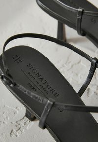 Schwarze Absatzsandalen mit dünnen Riemen, strukturiertem Fußbett und Blockabsatz. Mit "SIGNATURE" gekennzeichnet, hergestellt in Brasilien, Größe 6,5/40.