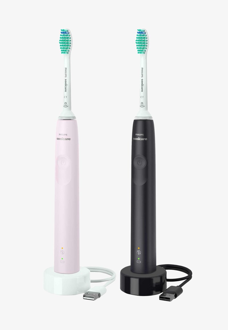 Deux brosses à dents électriques en rose et noir, avec des poignées courbées, des poils multicolores et des bases de chargement ; câbles USB inclus.
