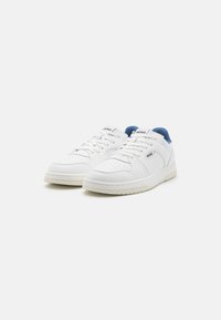 White leather sneakers with blue accents and perforated detailing. Features textured soles, flat laces, and branding on the tongue.