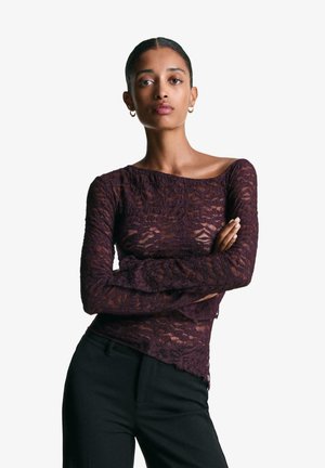 Top a maniche lunghe in pizzo borgogna con scollatura off-shoulder e intricati motivi floreali, abbinato a pantaloni neri su misura.