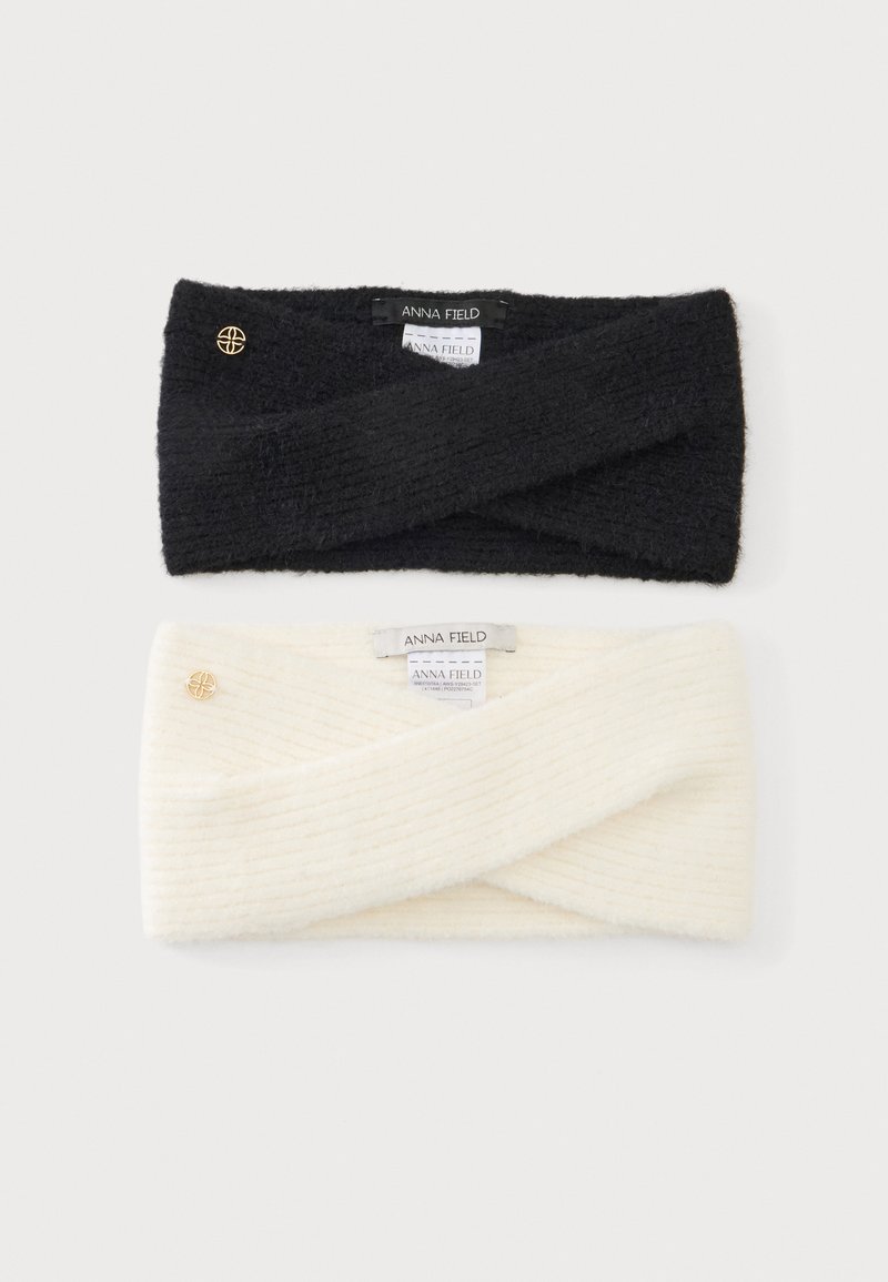 Deux bandeaux tricotés, un noir et un blanc, chacun avec un petit emblème doré et une étiquette portant la mention "Anna Field."