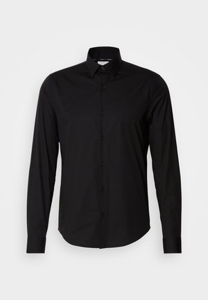 Czarna, długorękawowa koszula wykonana z gładkiego materiału. Posiada klasyczny kołnierzyk, zapięcie na guziki oraz prosty dół. Brak wzorów i akcentów.