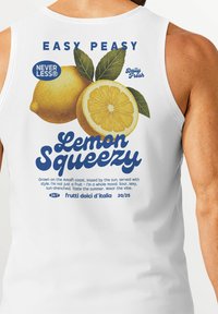 White sleeveless tank top featuring a lemon graphic, green leaves, and blue text with the phrase "Lemon Squeezy" and a brand logo.