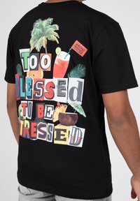 Camiseta de algodón negra con un gráfico colorido que presenta cócteles, fruta y un texto en negrita que dice "Demasiado bendecido para estar estresado."