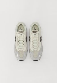 Paire de baskets New Balance 1000 blanches et grises vues de dessus sur un fond blanc uni.