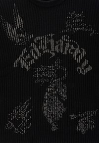 Top a costine nero con grafiche testurizzate in grigio, tra cui parole e simboli, con scollatura rotonda e design aderente.