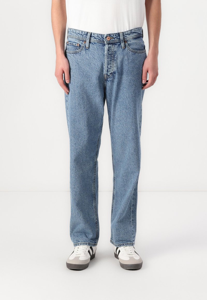 Jeans din denim albastru deschis cu un design cu picior drept, având un stil cu cinci buzunare și închidere cu nasture. Purtați cu adidași albi.