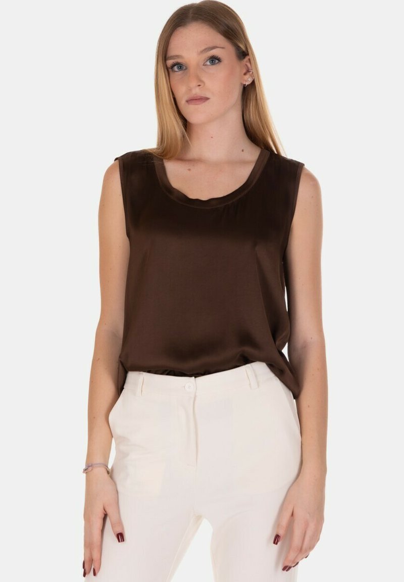 Top senza maniche in raso marrone con scollatura rotonda, texture liscia, cade delicatamente. Abbinato a pantaloni bianchi aderenti. Design semplice, accenti minimi.