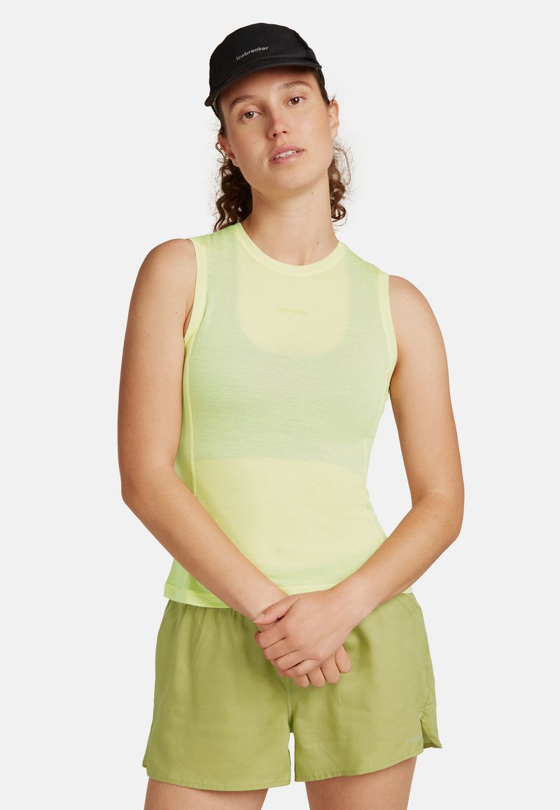 Top ligero sin mangas en tejido de malla amarillo brillante, combinado con pantalones cortos verdes. Presenta un cuello redondo y un logotipo discreto en el pecho.