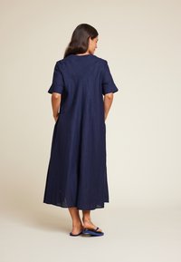 Mørkeblå, knelengde kjole laget av et teksturert stoff med korte oppbrettede ermer, som har en enkel fasong og ingen merkbare dekorasjoner.