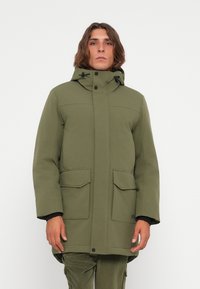 Groene parka jas met capuchon, voorzien van een voorkeursrits, twee grote opgestikte zakken en een gladde textuur. Ontworpen met een moderne pasvorm.