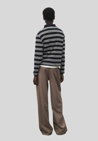 Polo a maniche lunghe a righe in navy e bianco, abbinato a pantaloni beige larghi, che mette in mostra un materiale in cotone e una vestibilità rilassata.