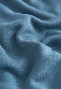 Zachte, textuurrijke stof in een gedempte blauwe kleur, met een licht gekreukt uiterlijk, dat de lichte en flexibele aard laat zien.