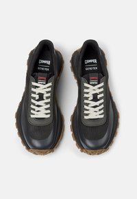 GORE-TEX hiking shoes with a black mesh upper, grey accents, beige laces, and rugged brown rubber soles.