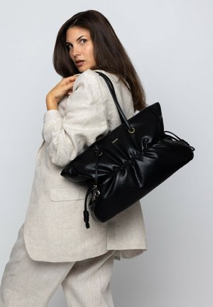 Schwarze Lederhandtasche mit gerafftem Design, goldenen Hardware-Akzenten und einem Kordelzugverschluss. Über der Schulter getragen.
