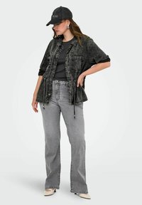 Črna usnjena jakna z dvema sprednjima žepoma, v paru s sivo majico in sivimi širokimi hlačami. Črna kapa in bež petke dopolnjujeta videz.